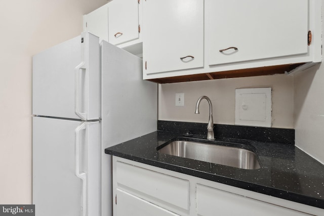 kitchen featuring white fridge, white cabinetry, and sink