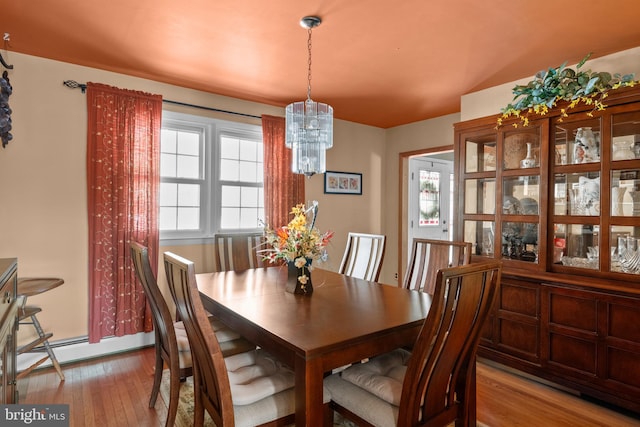 dining space featuring a baseboard heating unit, a notable chandelier, and light hardwood / wood-style floors