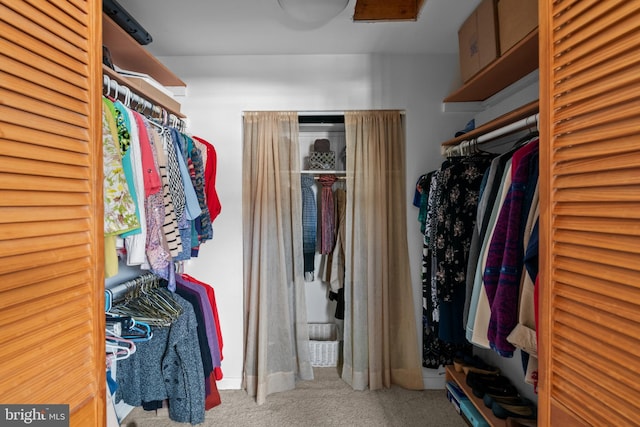 walk in closet with light carpet