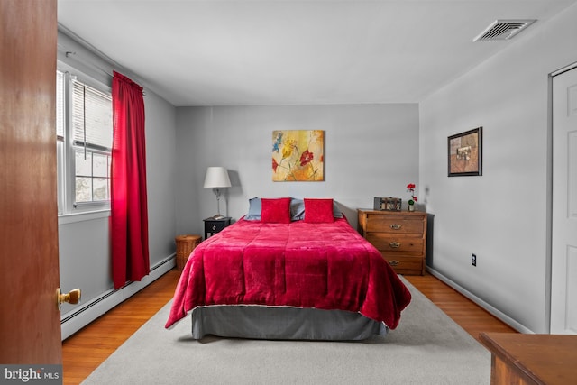 bedroom with light wood-type flooring and a baseboard radiator