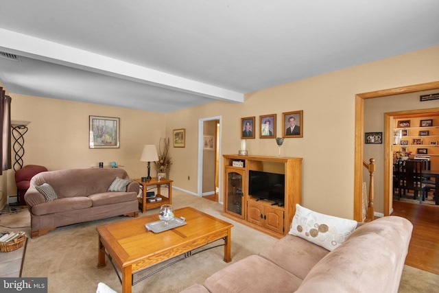 carpeted living room featuring beam ceiling