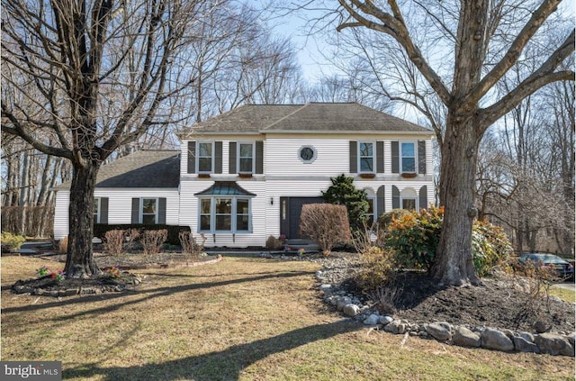 colonial home featuring a front lawn and a shingled roof