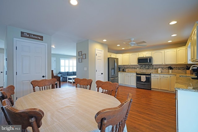 dining space featuring dark wood-type flooring, ceiling fan, and sink