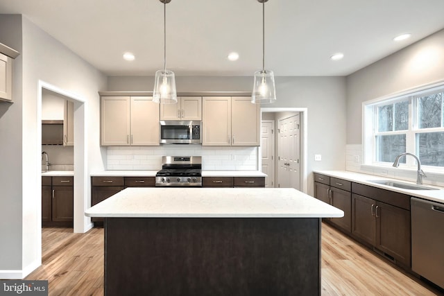 kitchen with light stone countertops, light wood-type flooring, stainless steel appliances, and sink