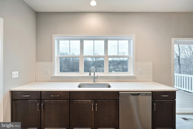 kitchen featuring stainless steel dishwasher, backsplash, sink, and a wealth of natural light