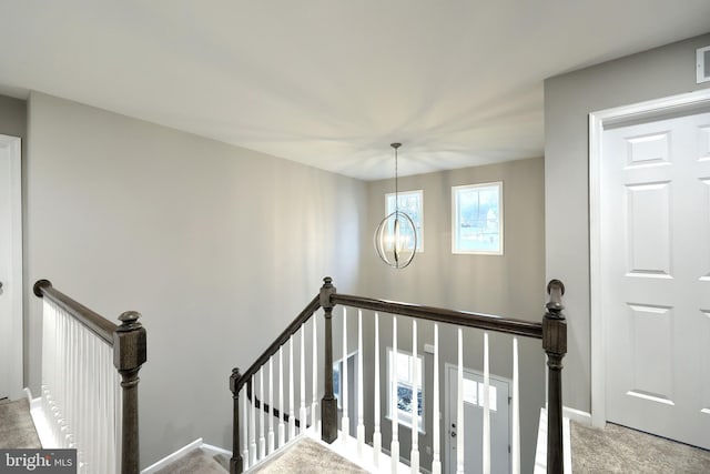 stairway featuring carpet floors and a notable chandelier