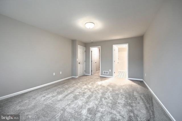 unfurnished bedroom featuring ensuite bathroom and carpet floors