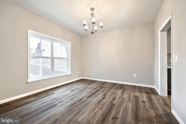 spare room with a chandelier and dark hardwood / wood-style floors