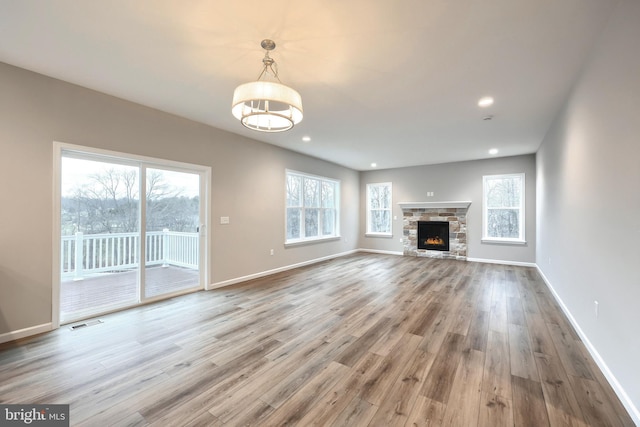 unfurnished living room with a stone fireplace and hardwood / wood-style floors