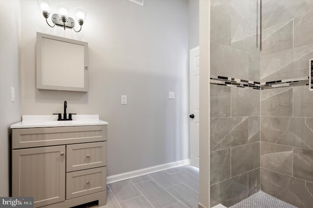 bathroom with tile patterned flooring, a tile shower, and vanity