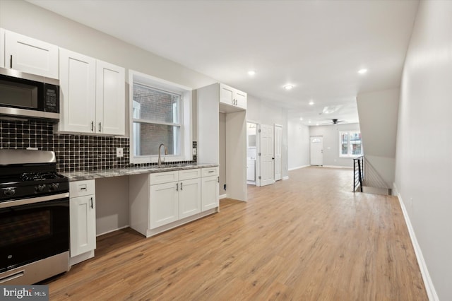 kitchen featuring white cabinets, ceiling fan, light wood-type flooring, light stone countertops, and stainless steel appliances