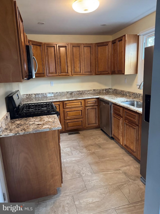 kitchen featuring sink, light stone countertops, and stainless steel appliances