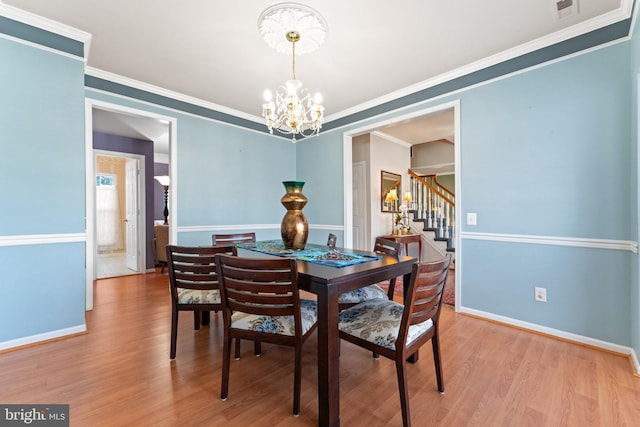 dining space featuring an inviting chandelier, ornamental molding, and light wood-type flooring