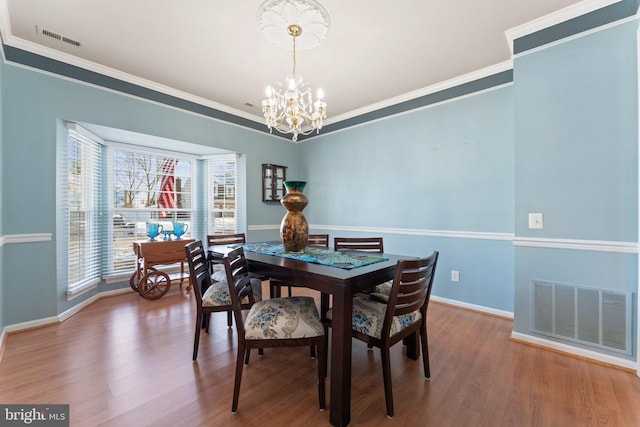 dining room featuring crown molding, wood-type flooring, and an inviting chandelier