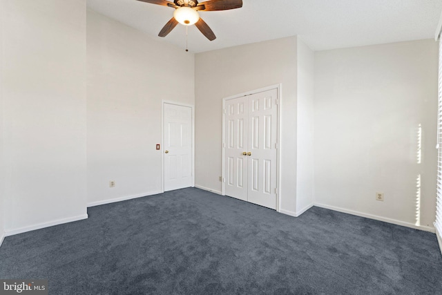 unfurnished bedroom featuring dark carpet, high vaulted ceiling, and ceiling fan