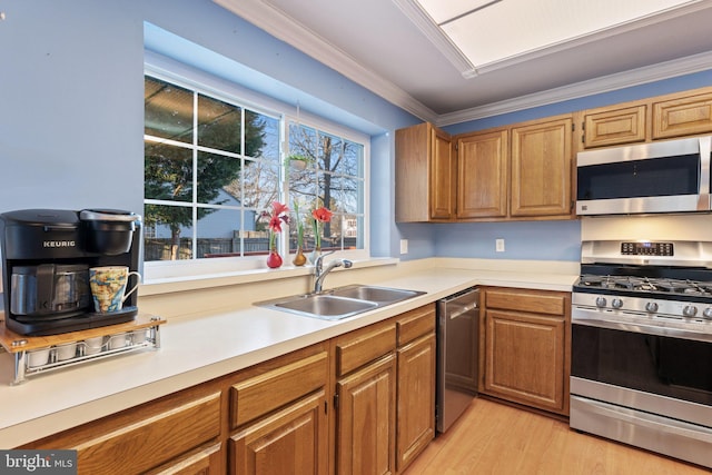 kitchen featuring sink, crown molding, light hardwood / wood-style flooring, and appliances with stainless steel finishes