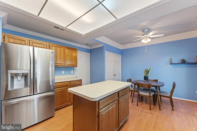 kitchen with crown molding, ceiling fan, a center island, stainless steel refrigerator with ice dispenser, and light wood-type flooring