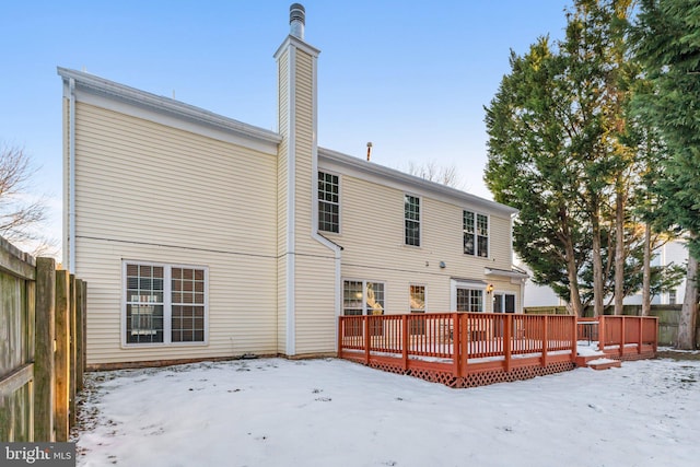 snow covered back of property with a deck