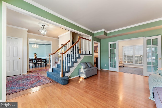 foyer with a notable chandelier, crown molding, and wood-type flooring