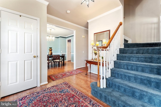 foyer entrance with crown molding, a chandelier, and hardwood / wood-style flooring