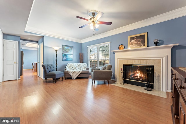 interior space with crown molding, ceiling fan, a fireplace, and light wood-type flooring