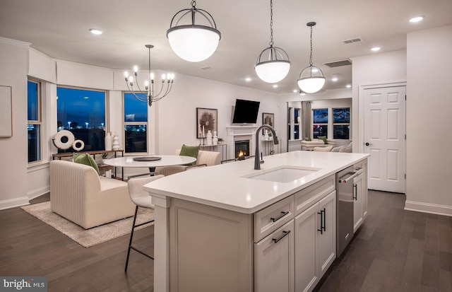 kitchen featuring a kitchen island with sink, sink, hanging light fixtures, dark hardwood / wood-style flooring, and white cabinetry