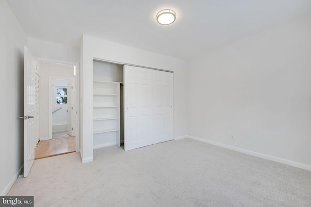 unfurnished bedroom with light colored carpet and a closet