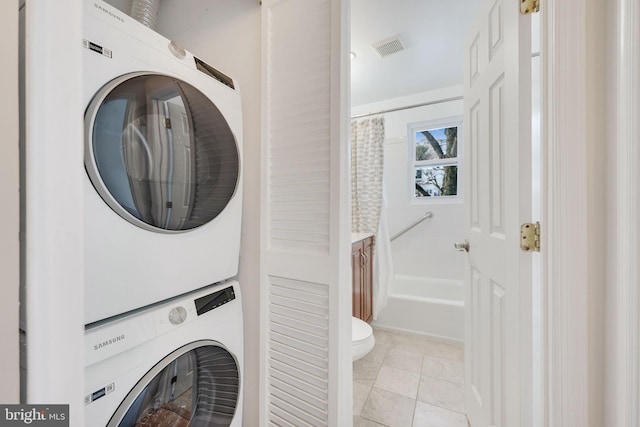 laundry room featuring stacked washer / dryer and light tile patterned flooring