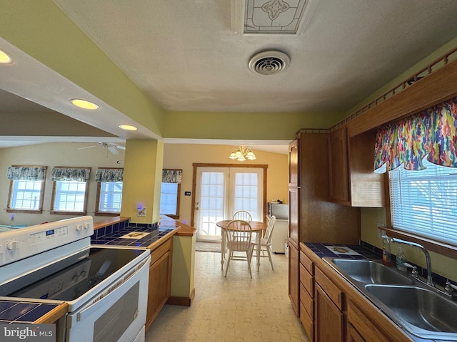 kitchen featuring white electric stove, tile counters, a wealth of natural light, and sink