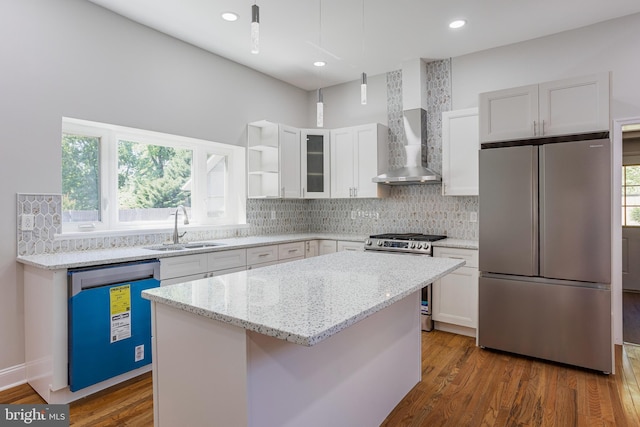 kitchen featuring a center island, white cabinets, sink, wall chimney exhaust hood, and appliances with stainless steel finishes