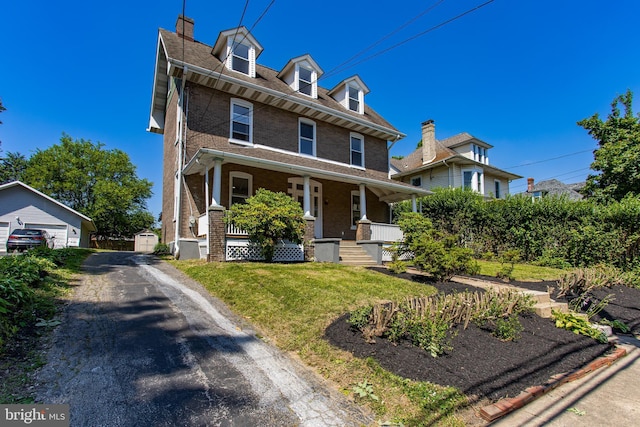 view of front of house with covered porch, a front lawn, and an outdoor structure