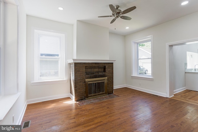 unfurnished living room featuring dark hardwood / wood-style floors, ceiling fan, sink, and a brick fireplace