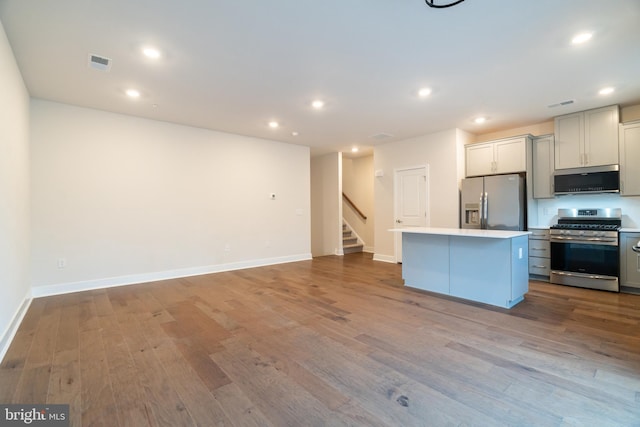 kitchen with appliances with stainless steel finishes, gray cabinets, light hardwood / wood-style flooring, and a kitchen island