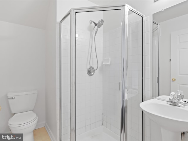 bathroom featuring a shower with door, sink, and toilet