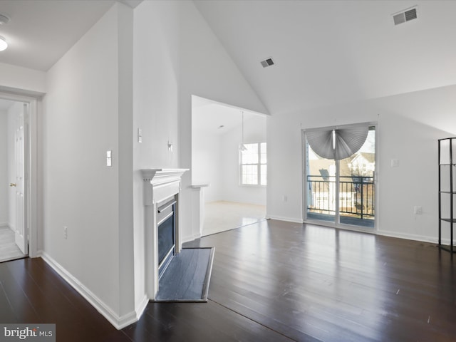 unfurnished living room with dark hardwood / wood-style flooring and high vaulted ceiling