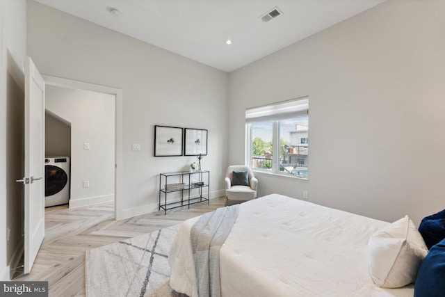 bedroom with light parquet flooring and washer / dryer