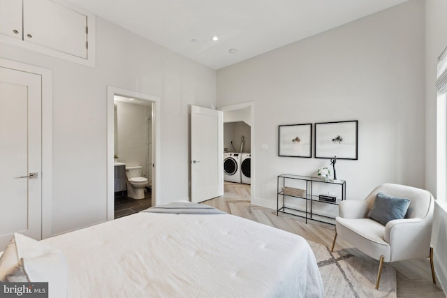 bedroom featuring light parquet flooring, ensuite bathroom, and washing machine and clothes dryer