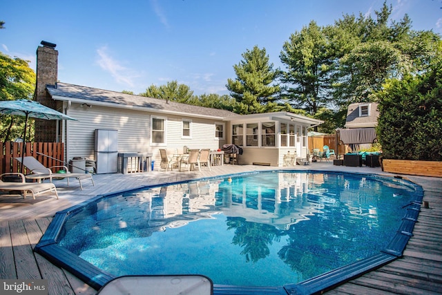 view of pool featuring a sunroom, outdoor lounge area, and a wooden deck