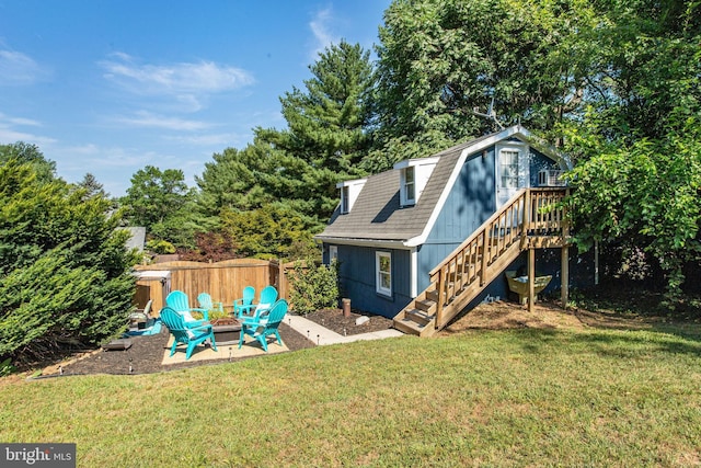 back of property featuring a patio area, an outdoor fire pit, a wooden deck, and a lawn