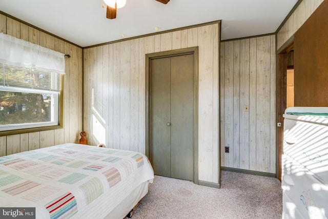 carpeted bedroom featuring wood walls, ceiling fan, and a closet