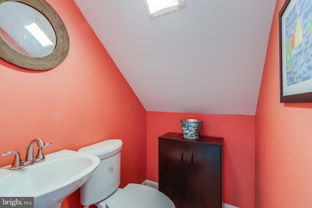 bathroom featuring sink, vaulted ceiling, and toilet