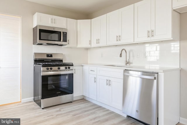 kitchen featuring sink, white cabinets, light wood-type flooring, and appliances with stainless steel finishes