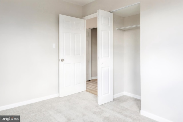 unfurnished bedroom with light colored carpet and a closet