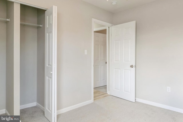 unfurnished bedroom with light carpet and a closet