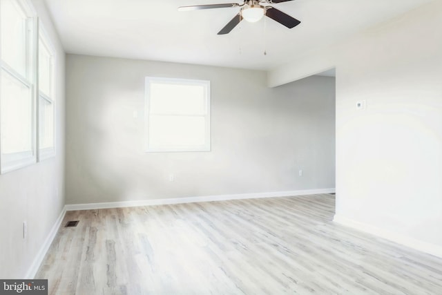 empty room with a wealth of natural light, light hardwood / wood-style flooring, and ceiling fan