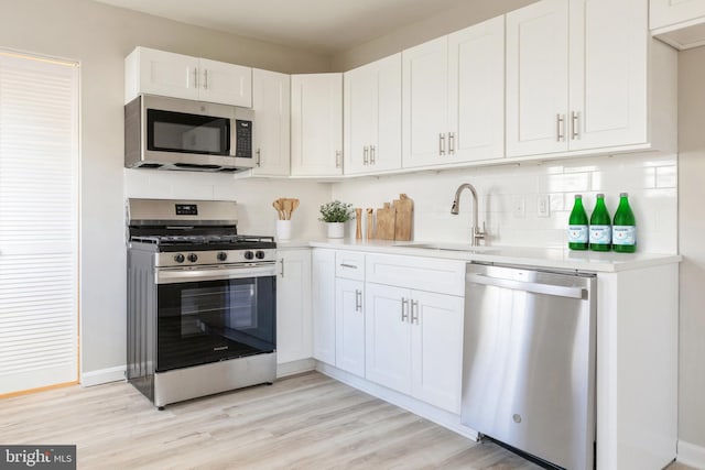 kitchen with white cabinets, appliances with stainless steel finishes, light wood-type flooring, and sink