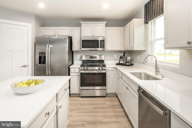 kitchen featuring white cabinets, appliances with stainless steel finishes, light hardwood / wood-style flooring, and sink