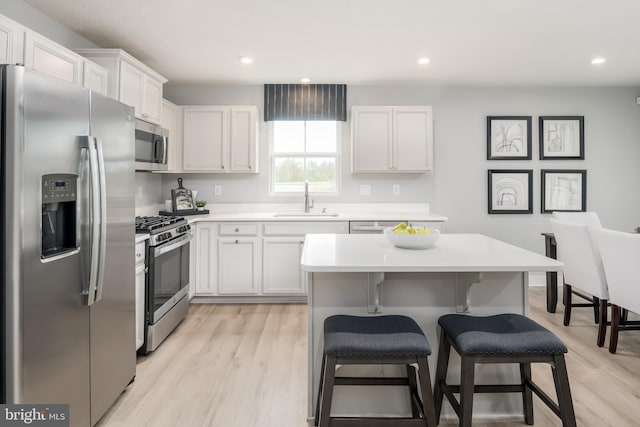 kitchen featuring white cabinets, a kitchen breakfast bar, sink, and stainless steel appliances