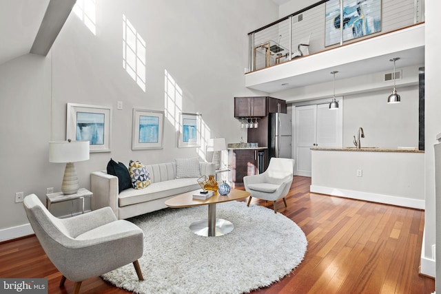 living room with a towering ceiling, sink, and hardwood / wood-style floors