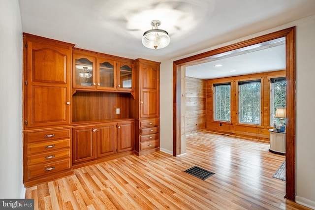 unfurnished dining area featuring wood walls and light hardwood / wood-style flooring